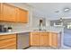 Kitchen with wooden cabinets, stainless steel dishwasher, and a view to the living room and backyard at 16188 W Hearn Rd, Surprise, AZ 85379