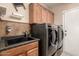 Functional laundry room featuring modern washer and dryer, cabinets, sink, and tiled backsplash at 16256 S 1St St, Phoenix, AZ 85048