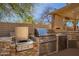 Outdoor kitchen with stainless steel grill, cooktop, and sink set in stone counters and brick surround at 16256 S 1St St, Phoenix, AZ 85048