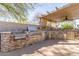 Inviting outdoor kitchen with stainless steel appliances, stone accents, and shaded pergola at 16256 S 1St St, Phoenix, AZ 85048