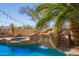 Beautiful pool with a waterfall, slide, and spa surrounded by palm trees and desert plants at 16256 S 1St St, Phoenix, AZ 85048