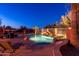 Lush backyard featuring a sparkling swimming pool with a rock waterfall, surrounded by desert landscaping at 17708 W Cactus Flower Dr, Goodyear, AZ 85338