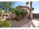 Landscaped view of the home showing the detached garage, gravel groundcover, and manicured shrubs and trees at 18261 W Weatherby Dr, Surprise, AZ 85374