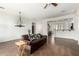 Spacious living room with tiled floors, a brown leather sofa, and an open view to the kitchen area at 18261 W Weatherby Dr, Surprise, AZ 85374