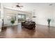 Bright living room featuring a brown leather sofa, tile flooring, and sliding glass doors to the backyard at 18261 W Weatherby Dr, Surprise, AZ 85374