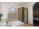 Modern bathroom featuring a bathtub and separate glass shower with neutral tile and a curved window at 1915 E Citation Ln, Tempe, AZ 85284