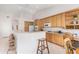 Spacious kitchen featuring natural wood cabinetry, breakfast bar, and white appliances at 20386 E Bronco Dr, Queen Creek, AZ 85142