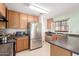 Well-lit kitchen features stainless steel appliances, wood cabinets, and dark countertops at 21876 W Mohave St, Buckeye, AZ 85326