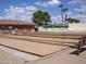 Well-maintained bocce ball court with multiple lanes, surrounded by seating and a charming building under a sunny sky at 2416 N Snead Dr, Mesa, AZ 85215