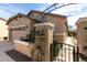 Stone column and wrought iron gate with vine covered trellis framing home's entrance at 26057 W Sequoia Dr, Buckeye, AZ 85396