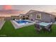 Stunning backyard pool featuring artificial turf, outdoor dining, and decorative string lights at dusk at 28883 N 131St Dr, Peoria, AZ 85383