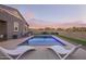 Inviting backyard pool featuring stylish lounge chairs and decorative string lights at dusk at 28883 N 131St Dr, Peoria, AZ 85383