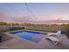 Inviting backyard pool featuring stylish lounge chairs and decorative string lights at dusk at 28883 N 131St Dr, Peoria, AZ 85383