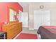 Bedroom with wooden dresser, light grey floors, and a red accent wall at 28883 N 131St Dr, Peoria, AZ 85383