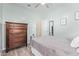 Light and airy bedroom with wood-look floors, a ceiling fan and a dark wooden dresser at 28883 N 131St Dr, Peoria, AZ 85383
