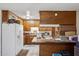 Functional kitchen featuring wood cabinets, tiled floors, and standard white appliances ready for updates at 4020 W Tuckey Ln, Phoenix, AZ 85019