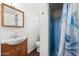 Bathroom featuring a wooden vanity, sink, mirror, toilet, and tiled shower with a blue flower shower curtain at 4245 N 16Th Dr, Phoenix, AZ 85015
