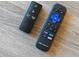 Close-up of two TV remotes on a wood-grained surface, featuring popular streaming app buttons at 4245 N 16Th Dr, Phoenix, AZ 85015