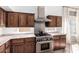 Close-up of kitchen features stainless steel oven and range with vent hood, and beautiful wood cabinets at 741 W Harvard Ave, Gilbert, AZ 85233