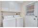 Bright laundry room with washer, dryer, storage cabinets and exterior access to the backyard at 829 S Revolta Cir, Mesa, AZ 85208