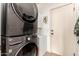 Modern gray stackable washer and dryer inside laundry room with door and shelving at 9260 E Greenway St, Mesa, AZ 85207