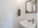 Stylish half-bath featuring a pedestal sink, a decorative mirror, and neutral wall color at 9405 W Palmer Dr, Peoria, AZ 85345
