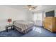 Cozy bedroom with a ceiling fan, a large window, neutral walls, and blue carpet at 9405 W Palmer Dr, Peoria, AZ 85345