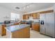 Close-up of the bright kitchen with an island, stainless steel appliances, wood cabinets, and blue countertops at 9405 W Palmer Dr, Peoria, AZ 85345