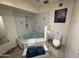 Bathroom featuring an unique shaped tub, tiled walls and toilet at 10013 W Alabama Ave, Sun City, AZ 85351