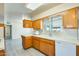 Spacious kitchen with wood cabinets, white appliances, tile countertops, and modern wood-look floors at 10025 W Alabama Ave, Sun City, AZ 85351