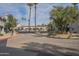 A landscaped gated entrance to a community featuring mature palm trees, cacti, and various businesses at 10115 E Mountain View Rd # 2042, Scottsdale, AZ 85258