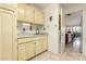 Laundry room with cream cabinets, sink and view to the living room at 10337 E Michigan Ave, Sun Lakes, AZ 85248