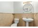 Charming powder room with a pedestal sink, decorative mirror, and neutral tile accents at 10616 E Carol Ave, Mesa, AZ 85208