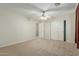 Bedroom featuring neutral carpet, ceiling fan, two closets, and entry door at 10616 E Carol Ave, Mesa, AZ 85208