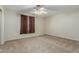 Bedroom featuring neutral carpet, a ceiling fan, and large window with curtains at 10616 E Carol Ave, Mesa, AZ 85208