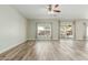 Bright living room featuring wood floors, a ceiling fan, and natural light from the sliding glass door to the backyard at 10616 E Carol Ave, Mesa, AZ 85208