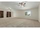 Large, carpeted living room boasting vaulted ceilings, ceiling fans and natural light from windows at 10616 E Carol Ave, Mesa, AZ 85208