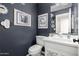 Stylish powder room with modern fixtures, patterned accent tiles, and decorative artwork on deep blue walls at 1202 E Milada Dr, Phoenix, AZ 85042