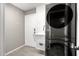 Laundry room featuring tile accent wall, gray walls, laundry sink and stacked washer dryer at 1202 E Milada Dr, Phoenix, AZ 85042