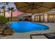 Beautiful backyard pool with a rock waterfall feature, covered patio, and lush tropical landscaping at 1202 E Milada Dr, Phoenix, AZ 85042