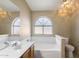 Bathroom featuring a large soaking tub beneath an arched window, creating a serene and inviting space at 1301 N Jackson St, Chandler, AZ 85225