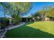 Lush backyard with artificial turf, mature trees, and covered patio perfect for outdoor relaxation at 1335 E Oregon Ave, Phoenix, AZ 85014