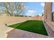 Well-manicured backyard with a patch of artificial lawn and a brick-paver patio at 13624 W Desert Moon Way, Peoria, AZ 85383