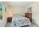 Cozy bedroom with a patterned bedspread, a dresser, and a nightstand with a lamp at 14432 W Yukon Dr, Sun City West, AZ 85375