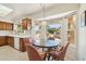 Charming eat-in kitchen area featuring warm wood cabinetry, a round glass table, and a bright view of the backyard at 14432 W Yukon Dr, Sun City West, AZ 85375