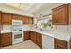 Well-lit kitchen featuring white appliances, ample cabinet space, and a window offering a pleasant view of the outdoors at 14432 W Yukon Dr, Sun City West, AZ 85375