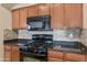 Updated kitchen features wood cabinetry, black appliances, and tile backsplash at 16102 W Miami St, Goodyear, AZ 85338