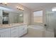 Bright bathroom featuring double sinks, soaking tub, glass shower enclosure, and natural light at 16409 W Alvarado Dr, Goodyear, AZ 85395