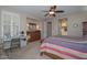 Comfortable bedroom featuring neutral walls, desk area, a ceiling fan, and an ensuite bathroom at 16409 W Alvarado Dr, Goodyear, AZ 85395