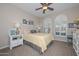 Cozy bedroom with carpet flooring featuring a queen bed, soft lighting, and two arched windows at 16409 W Alvarado Dr, Goodyear, AZ 85395